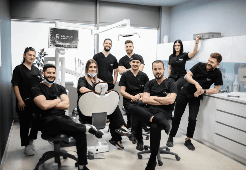 Dentisti e assistenti posano intorno a una poltrona nella sala di trattamento