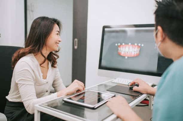 Dentist shows patient a 3D orthodontic treatment plan on computer screen