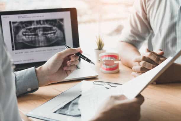 Dental professional reviews panoramic X-ray and treatment plan with patient during consultation
