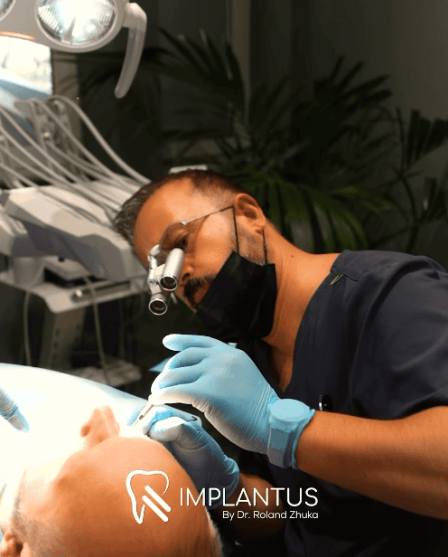 Dentist wearing magnifying loupes performs dental implant procedure on a reclined patient