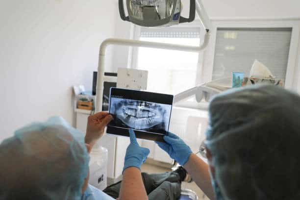 Dentists reviewing a panoramic dental x-ray on a tablet with patient