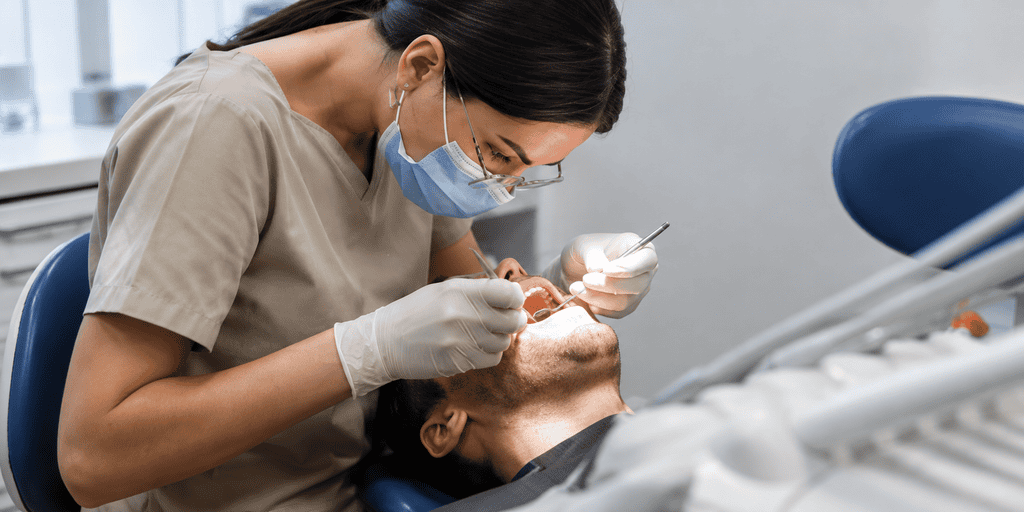 Close-up smile with metal braces; gloved hand gently retracts lip during orthodontic treatment.