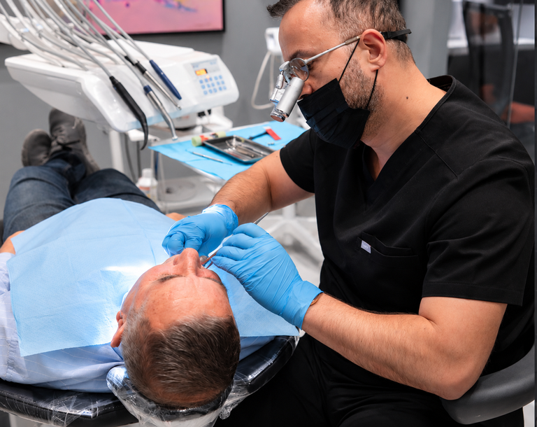 Dentiste réalisant un examen dentaire sur un patient à l’aide d’instruments dentaires.